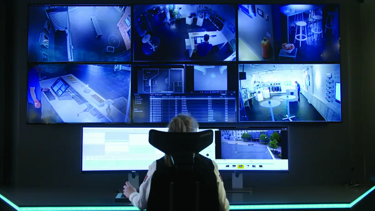 Security operator managing cameras from multi-screen VMS workstation
